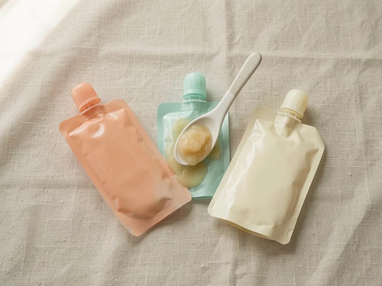 A row of squeezable baby food pouches on a pale surface, illustrating the products tested in the May 2026 Greenpeace investigation that found thousands of microplastic particles per pouch